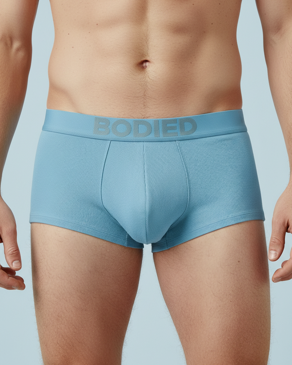 Light blue boxer briefs with 'Bodied' waistband on a light blue background