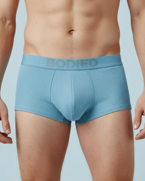 Light blue boxer briefs with 'Bodied' waistband on a light blue background